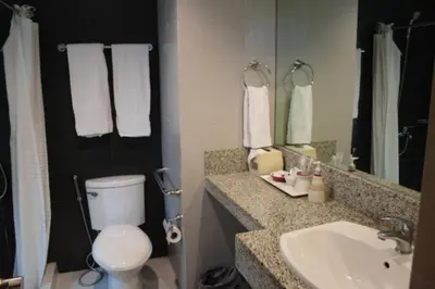 a bathroom with a toilet and a sink and a mirror at Festive Hotel Makati in Manila