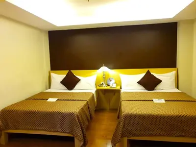 a room with two beds and a table with a lamp at Festive Hotel Makati in Manila