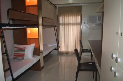 a small room with bunk beds and a desk and a chair at G Square Residences in Manila