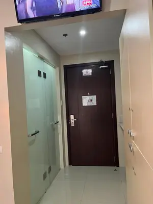 a bathroom with a brown door and a television at G Square Residences in Manila