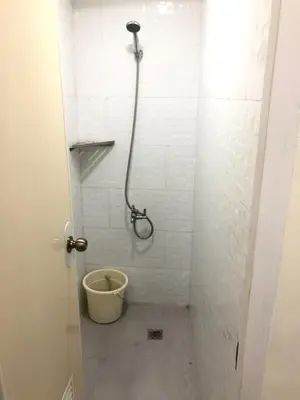 a bathroom with a shower with a bucket in it at Snoozeph in Manila