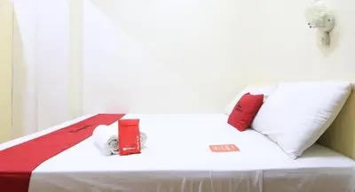 a white bed with red and white pillows on it at RedDoorz Plus @ Chinatown Binondo in Manila