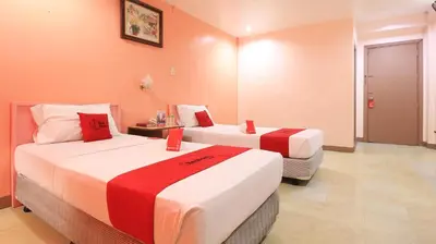 two beds in a hotel room with red and white sheets at RedDoorz Plus @ Chinatown Binondo in Manila