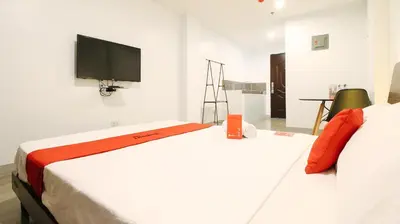 a bedroom with two beds and a flat screen tv at RedDoorz near Zobel Roxas St in Manila
