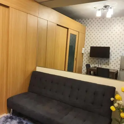 a living room with a couch in front of a mirror at SHELL RESIDENCES in Manila