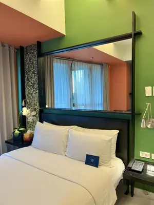 a bedroom with a large bed with a green wall at KL Serviced Residences Managed by HII in Manila