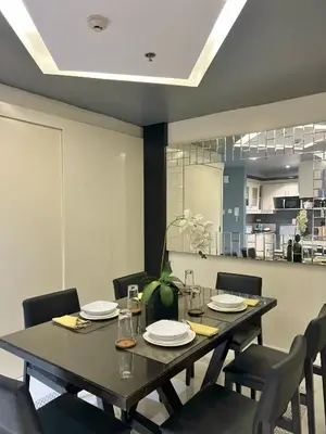 a dining room with a table and chairs and a kitchen at KL Serviced Residences Managed by HII in Manila
