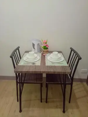 a dining room table with two chairs and a table with dishes at Spring Residence in Manila