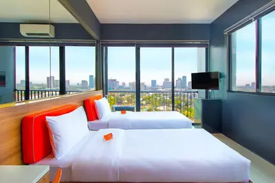 two beds in a room with a large window at Azumi Boutique Hotel in Manila