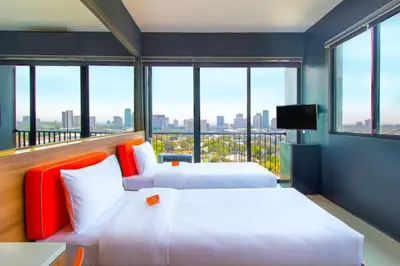 two beds in a room with a large window at Azumi Boutique Hotel in Manila