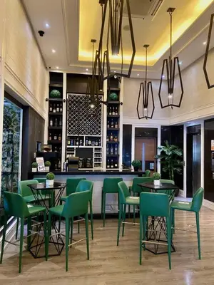 a restaurant with green chairs and tables and a bar at Azumi Boutique Hotel in Manila