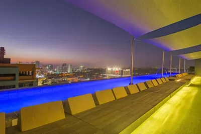 a rooftop pool with a view of the city at night at Azumi Boutique Hotel in Manila