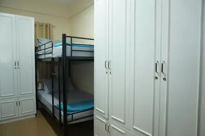 a room with two bunk beds and white cabinets at Mint Homes in CEV Mansion in Manila