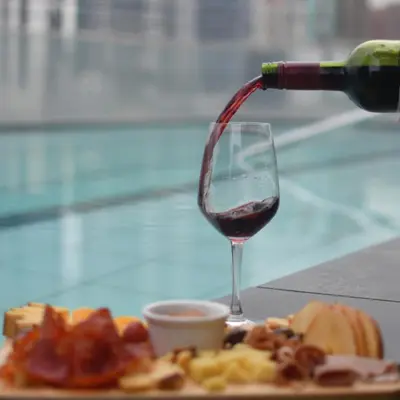 a person pouring wine into a glass next to a plate of food at Jade Hotel and Suites in Manila
