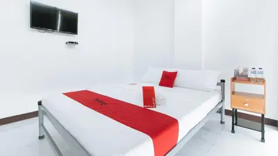 a bedroom with a white bed with a red blanket at RedDoorz at Good 101 Paranaque in Manila