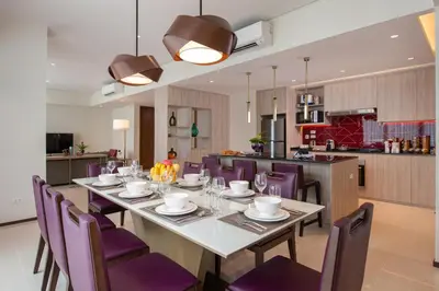 a dining room with a table and purple chairs at Somerset Central Salcedo Makati in Manila