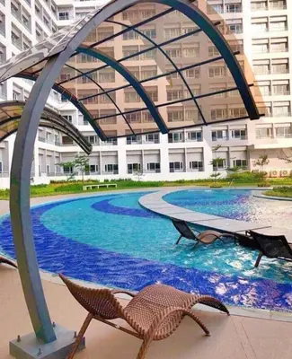 a swimming pool with two lounge chairs in front of a building at Taguig City Grace Residences with small balcony in Manila