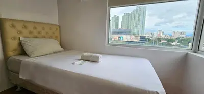 a white bed in a room with a window at Gilmore Tower Suites By SMS Hospitality in Quezon City