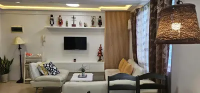 a living room with a couch and chairs and a tv at Gilmore Tower Suites By SMS Hospitality in Quezon City