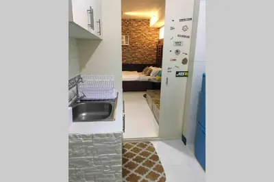 a kitchen with a sink and a room with a couch at CENTROPOLIS 4, Fun & Playful in Manila