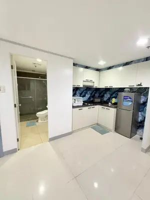 a kitchen with white cabinets and a white tile floor at Sea Residences at Jireh in Pasay