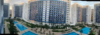 a view of a large building with pools and palm trees at Sea Residences at Jireh in Pasay