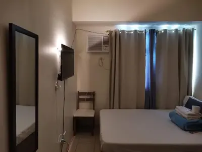 a bedroom with a bed and a mirror and a window at Mack's Awesome Place 24 with Netflix and FastUnliwifi in Manila