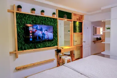 a bedroom with a tv on a wall with fake grass at House of Citiflora Unit A in Manila