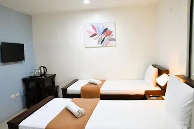 a small room with two beds and a tv at Arzo Hotel Makati in Manila
