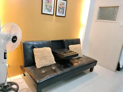 a black leather couch in a living room with a fan at Vangie's Place at SEA RESIDENCES in Manila