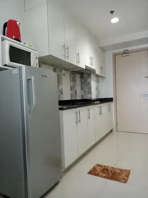 a kitchen with a stainless steel refrigerator and white cabinets at SEA RESIDENCES F in Manila
