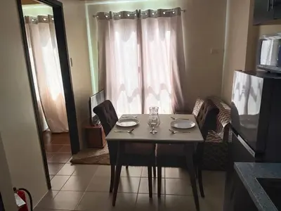 a dining room table with two plates and glasses on it at The Rochester Condo in Manila