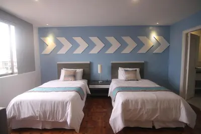 two beds in a room with blue walls at Bryan Condo Suites Makati near Airport in Manila