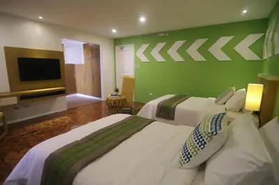 a bedroom with two beds and a green wall at Bryan Condo Suites Makati near Airport in Manila