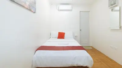 a bed in a white room with a red pillow at Nearest Hostel Pasay City by RedDoorz in Manila
