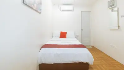 a small bedroom with a bed with an orange pillow at Nearest Hostel Pasay City by RedDoorz in Manila