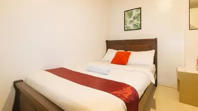 a bedroom with a bed with an orange pillow on it at Nearest Hostel Pasay City by RedDoorz in Manila