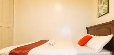 a bedroom with a bed with orange and white pillows at Nearest Hostel Pasay City by RedDoorz in Manila