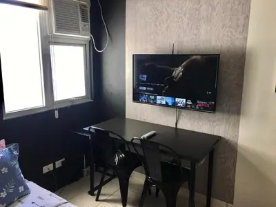 a room with a table and a television on a wall at Ronz Deca Hills in Manila