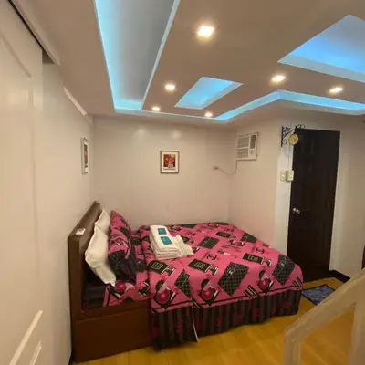 a bedroom with a bed with a pink comforter at MidKnight Sky Unit for Rent in Anabu Primero