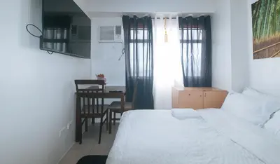 a bedroom with a bed and a table and a chair at Eimys Place at Urban Deca Mandaluyong by RedDoorz in Manila