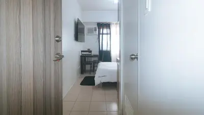 a hallway with a room with a bed and a door at Eimys Place at Urban Deca Mandaluyong by RedDoorz in Manila