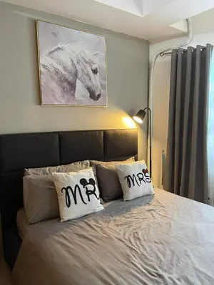a bedroom with a bed with two monogrammed pillows at MOA staycation Shell Residences Pasay city darpm in Manila