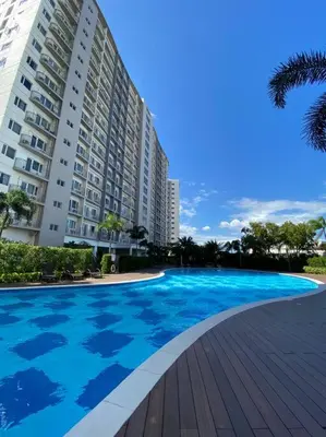 a large blue swimming pool next to a building at A Cozy 1 Bedroom Unit with a Parking at Tower 2 South Residences SM Southmall in Manila