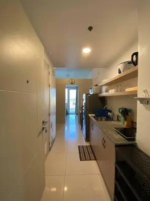 a kitchen with white cabinets and a long hallway at A Cozy 1 Bedroom Unit with a Parking at Tower 2 South Residences SM Southmall in Manila