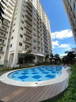 a swimming pool in front of a large building at A Cozy 2 Bedroom Unit with a Parking at Tower 2 South Residences SM Southmall in Manila