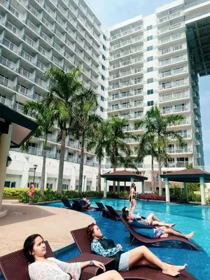 a group of people laying in chairs in a swimming pool at SHORE RESIDENCE d6, shortwalk Mall of Asia near Airport in Manila