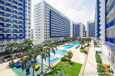 a resort with a pool and palm trees and buildings at Moa's Spot at Sea Residences in Manila