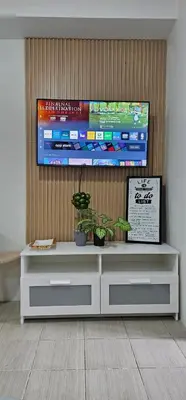 a television on top of a white cabinet with plants at Your Crib - kasara -19 D tower 1 in Manila