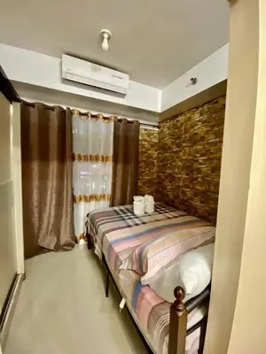 a bedroom with a bed and a brick wall at Azenith Staycation At Sea Residences Moa in Manila